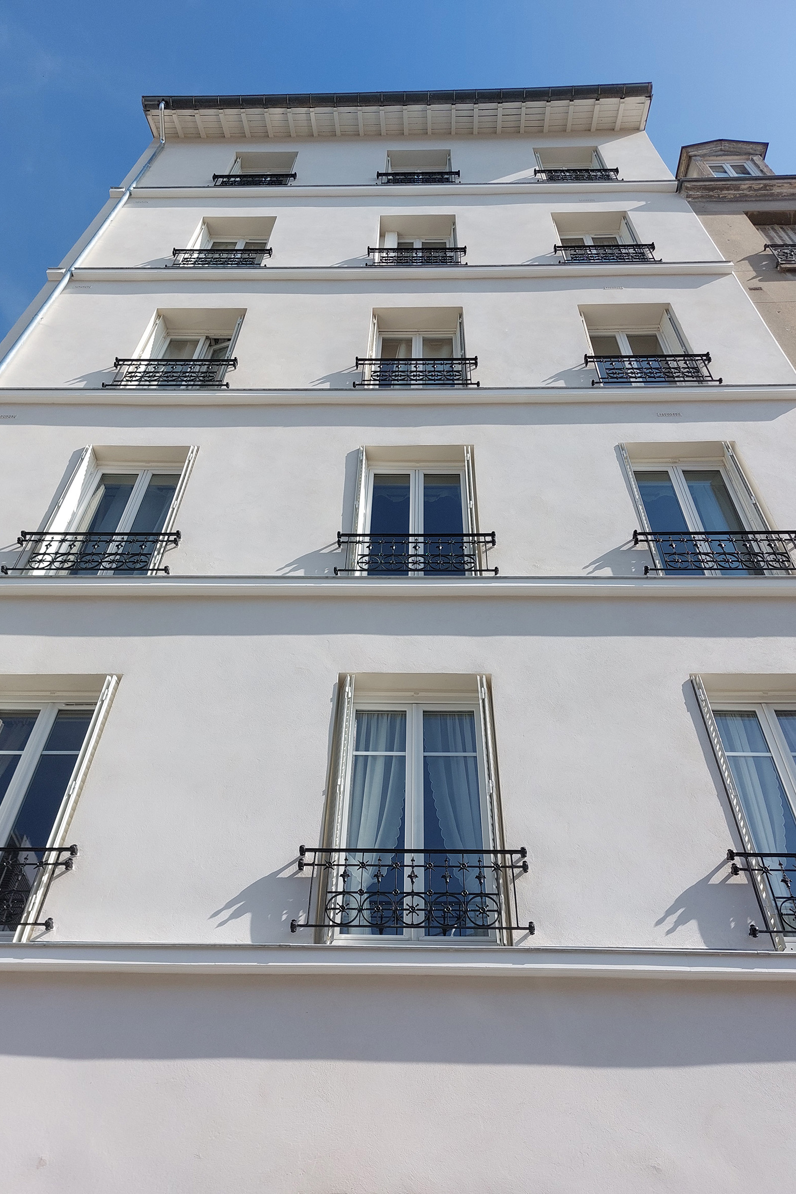 Détail de la façade rénovée avec enduit à la chaux et garde-corps métalliques