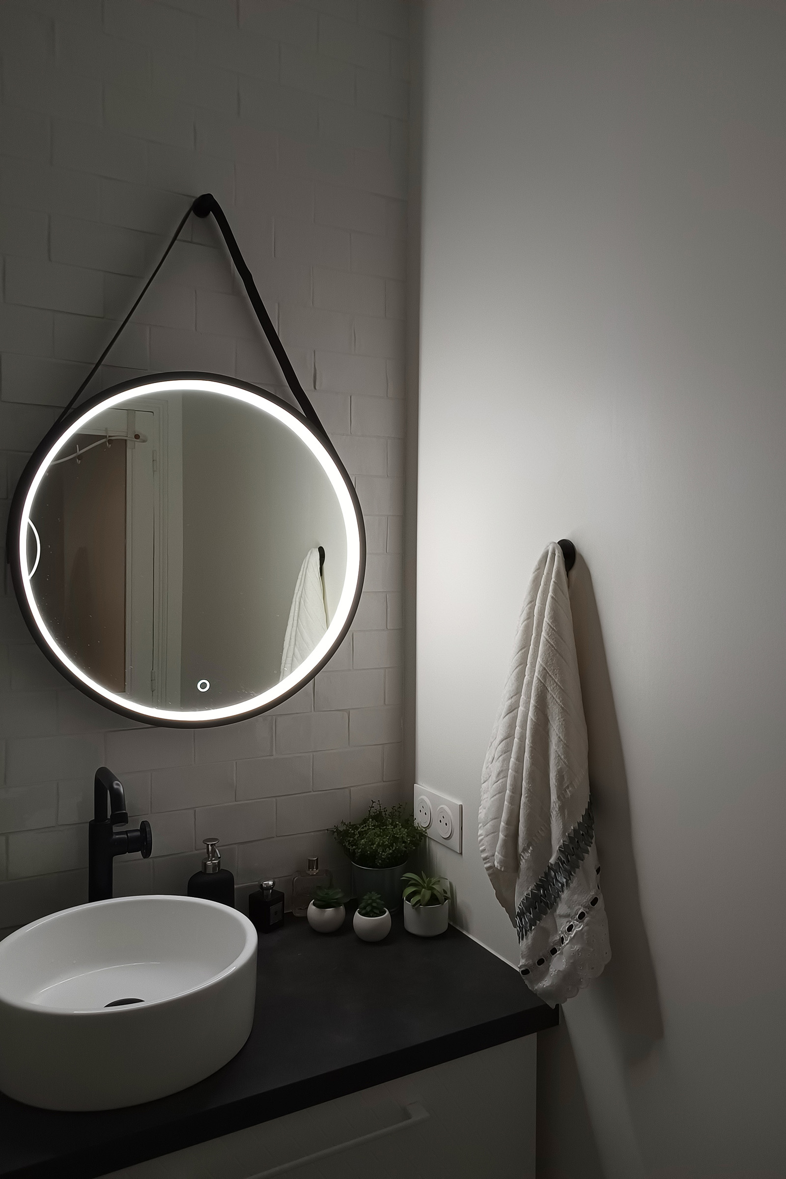 Salle de bains rénovée avec vasque et miroir rond rétroéclairé
